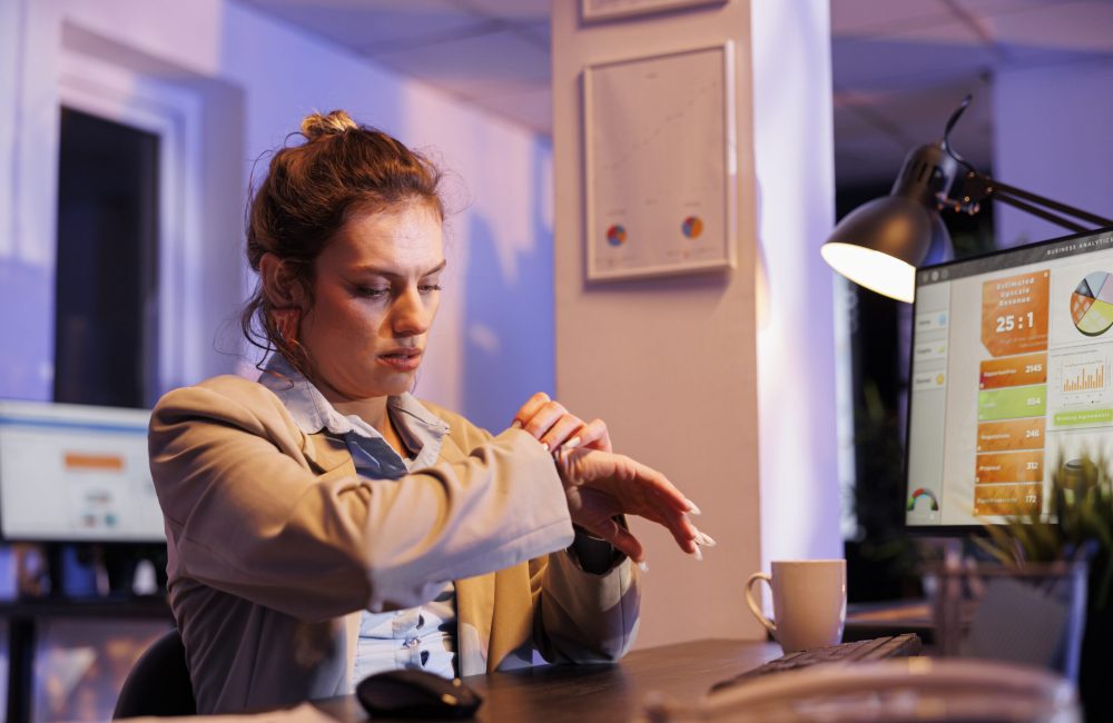 Executive manager checking time on wristwatch after working overtime at company investment strategy in startup office. Careful businesswoman analyzing marketing statistics. Corporate concept